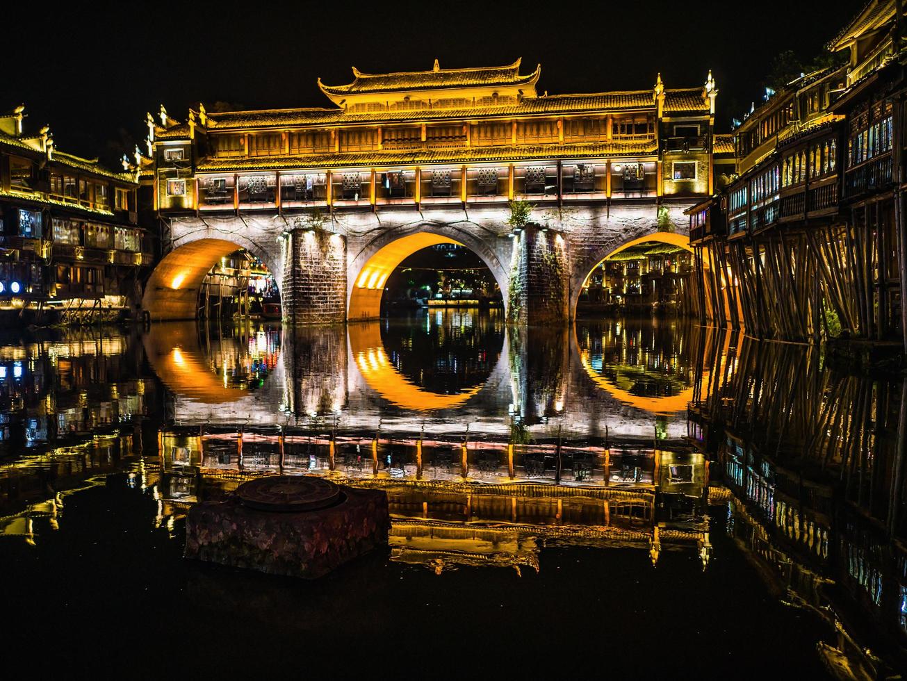 vista del paisaje del puente hong y el edificio en la noche del casco antiguo de fenghuang. la ciudad antigua de phoenix o el condado de fenghuang es un condado de la provincia de hunan, china foto