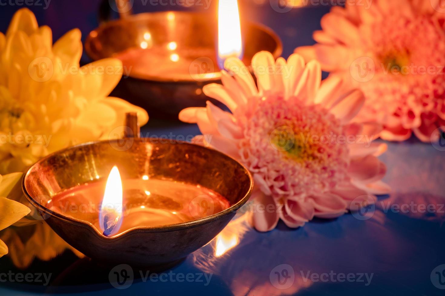 Happy Diwali. Burning diya oil lamps and flowers on blue background. Traditional Indian festival of light. photo