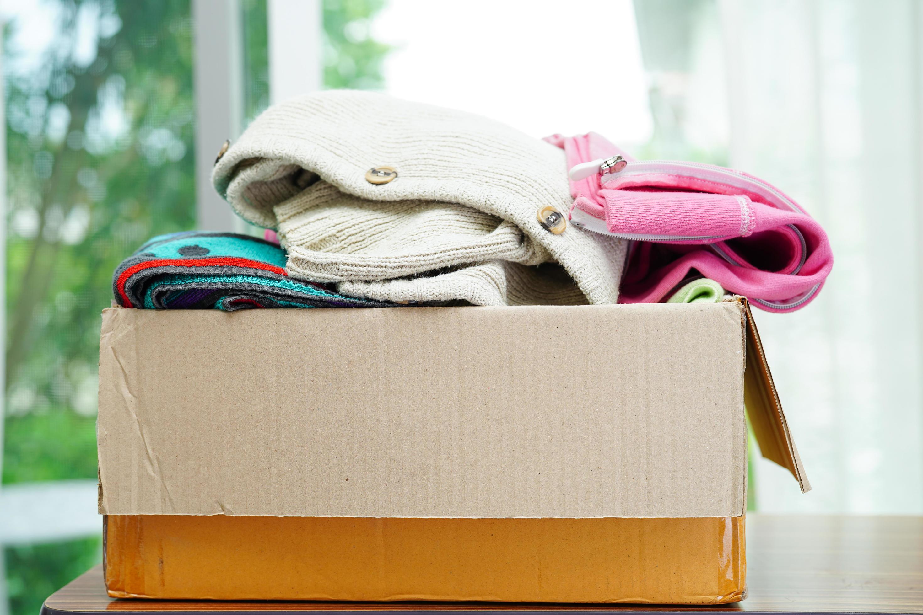Clothes donations in cardboard box for volunteer. 12346926 Stock Photo