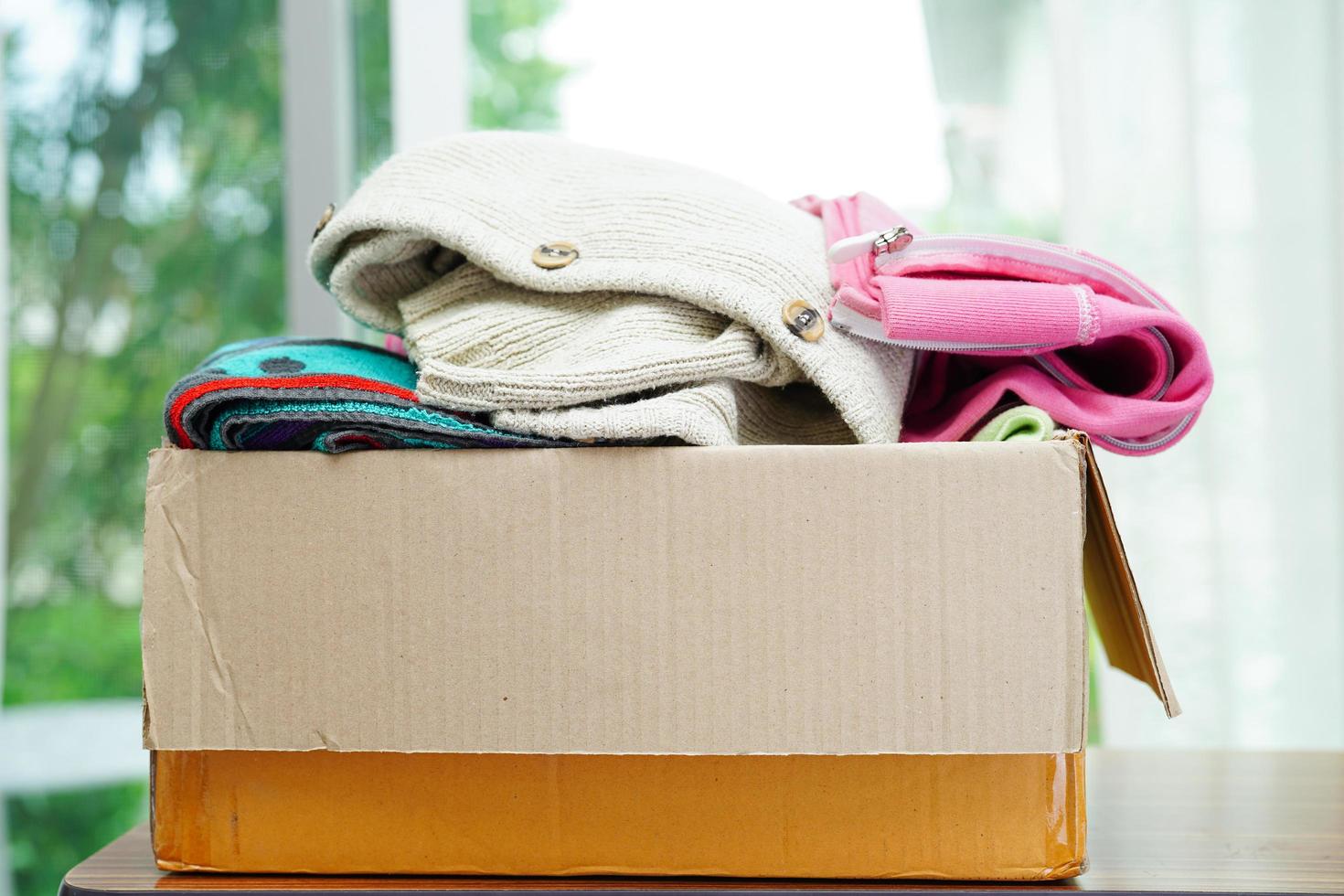 Clothes donations in cardboard box for volunteer. photo