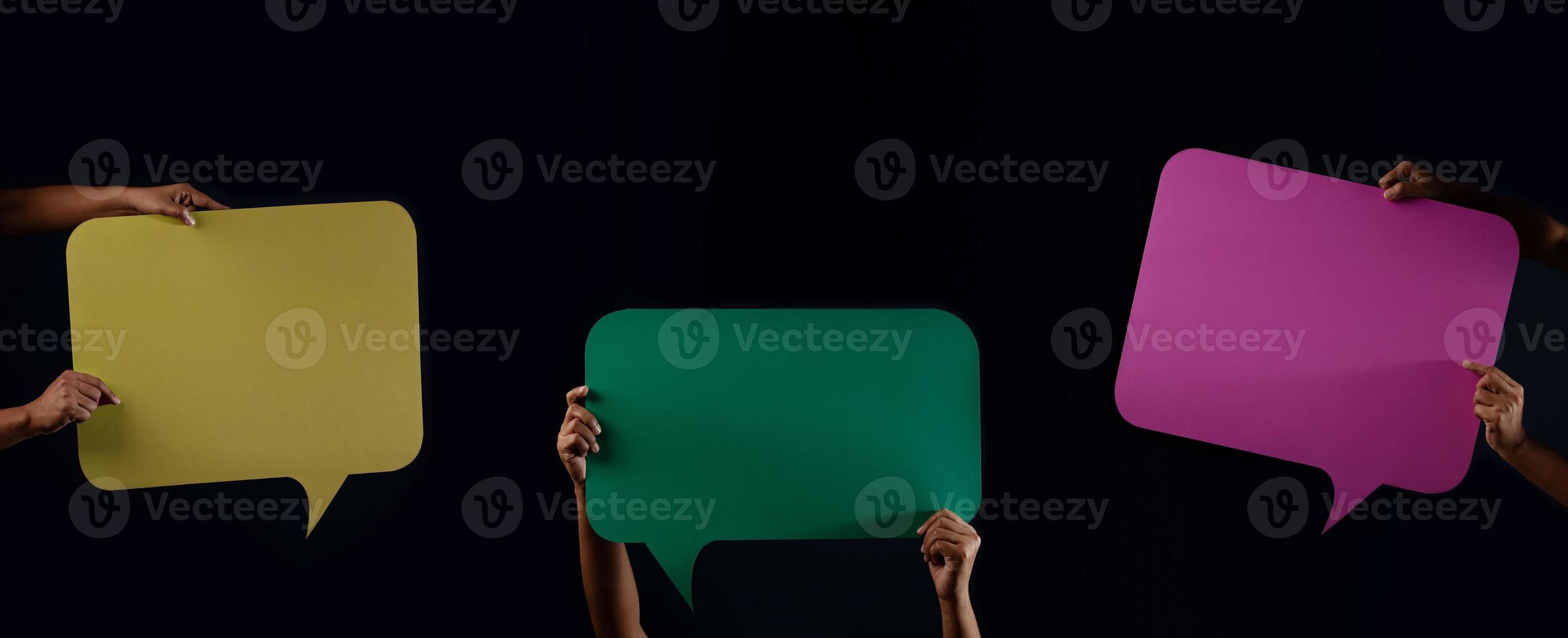 colorido bocadillo de diálogo en blanco. concepto de protesta o libertad de expresión. grupo de personas levantó papel de discurso vacío foto