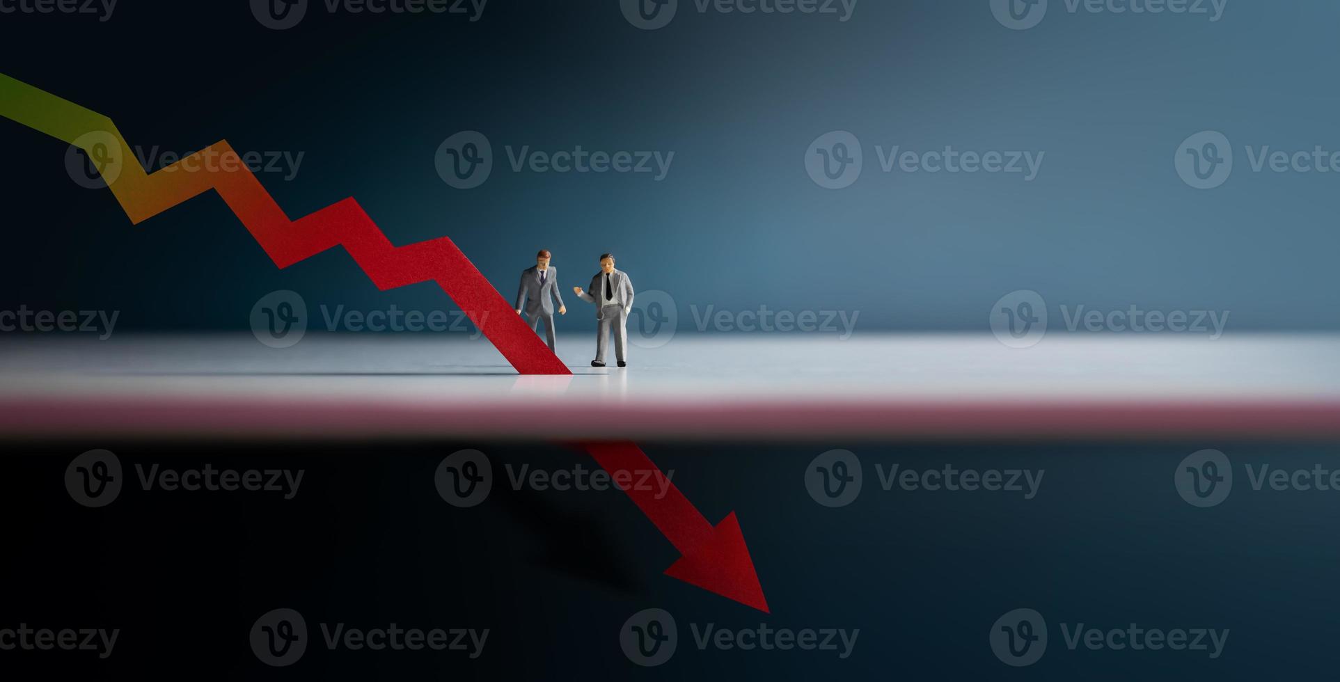 Recession, Inflation and Depression Concepts. Economic Crisis. Graph Fall Down, Business Collapse. Two Miniature Figure of Businessman Looking at a Red Graph Arrow Down photo