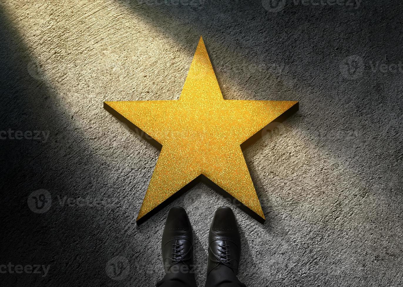 Success in Business or Personal Talent Concept. Top View of Businessman in Shiny Oxford Shoes standing in front of a Golden Star on the Dark Cement Floor photo
