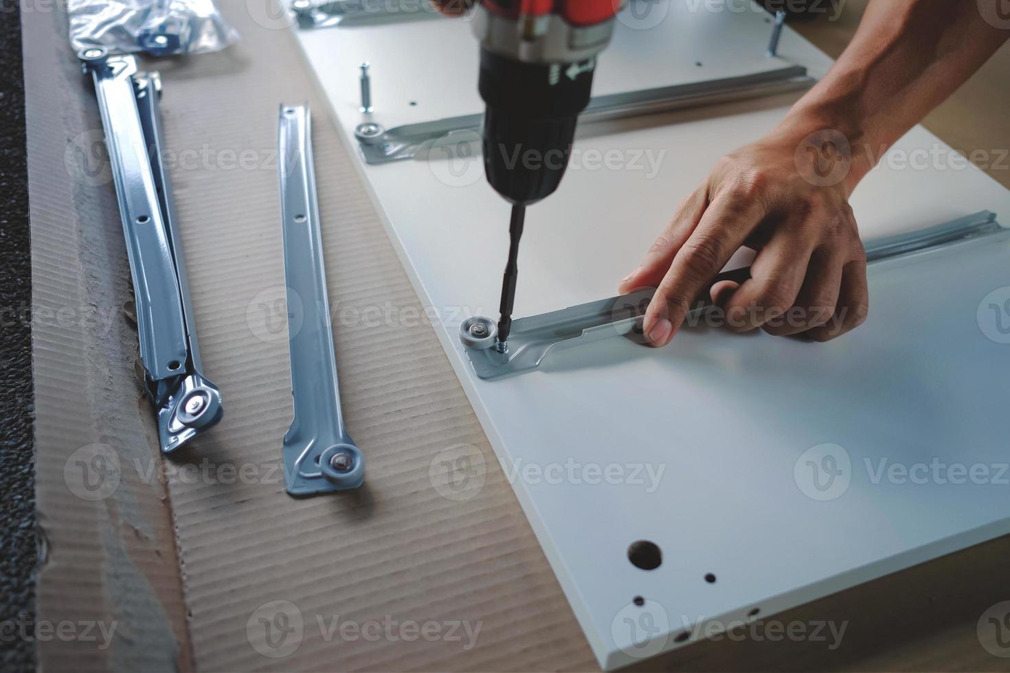 Assembling Furniture at Home. Moving for a New House or DIY Concept. Craftsman using Cordless Screwdriver to Installing the Cabinet to Installing the Cabinet. photo