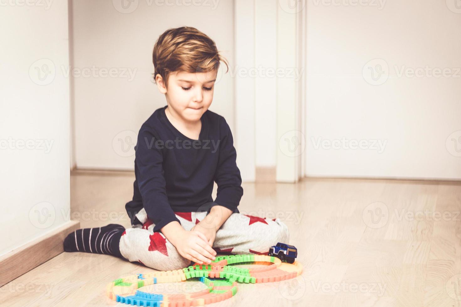 niño pequeño jugando con un coche de juguete en casa. foto