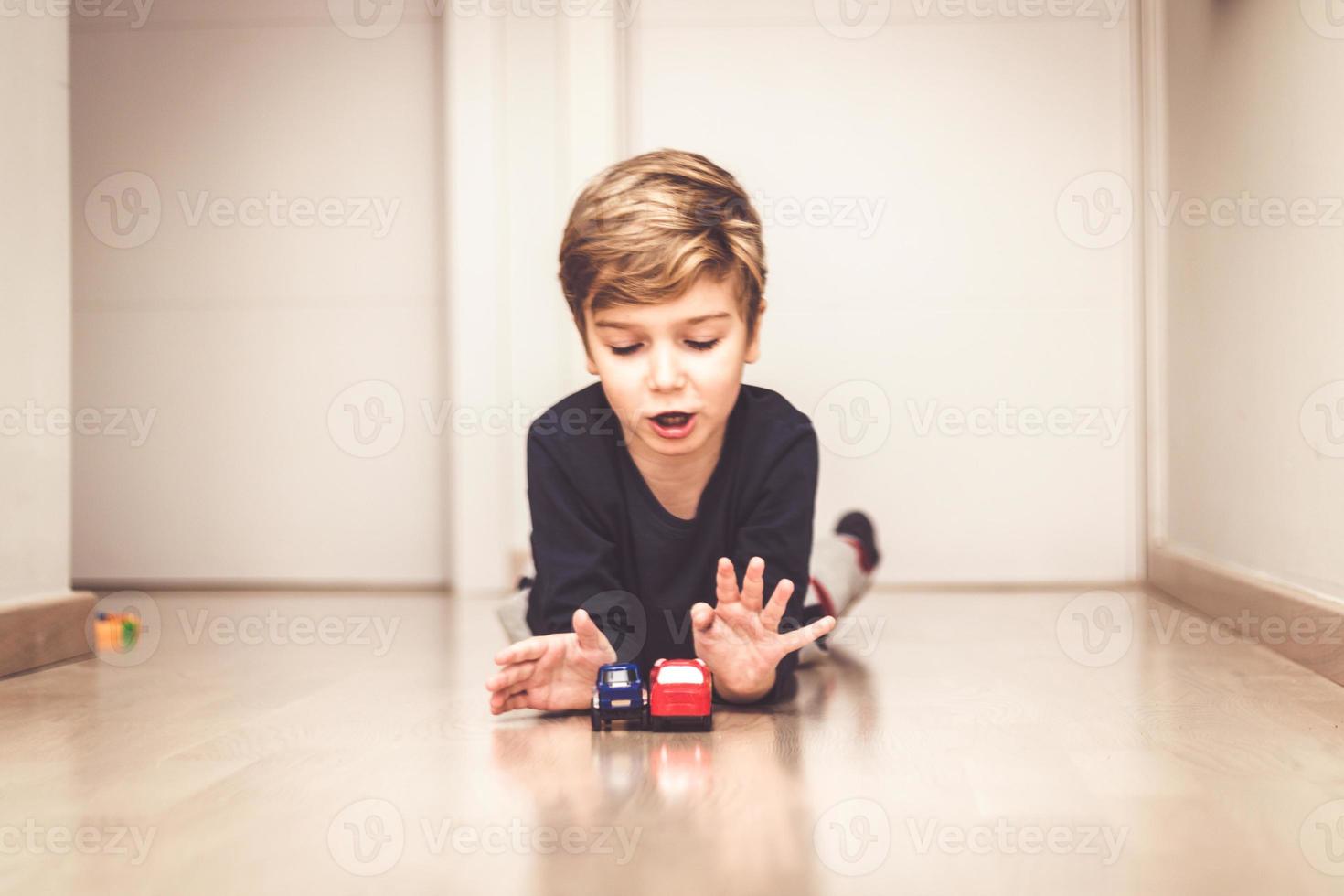 lindo niño jugando con juguetes de coche en el suelo. foto