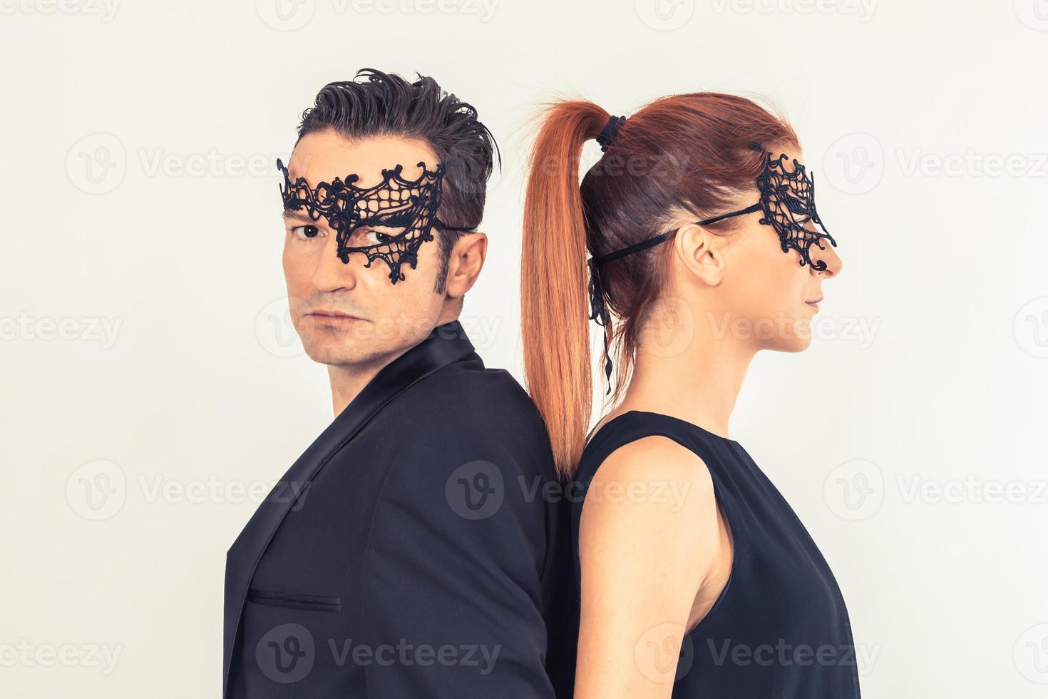 Couple wearing black face masks while standing back to back. photo