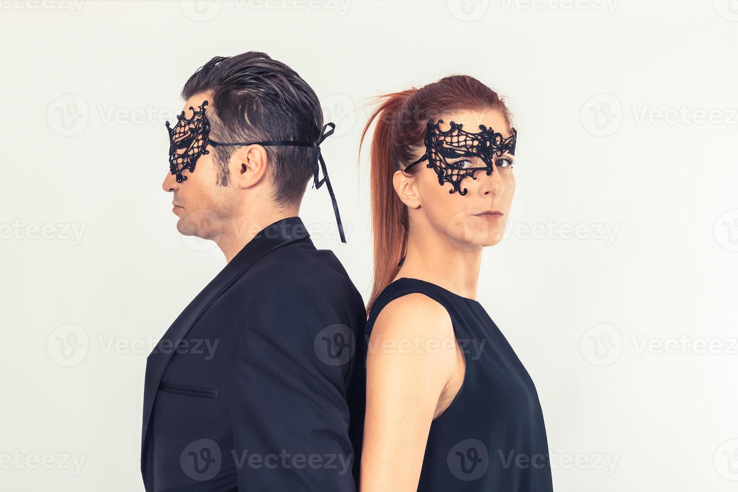 Couple with black face masks while standing back to back. photo
