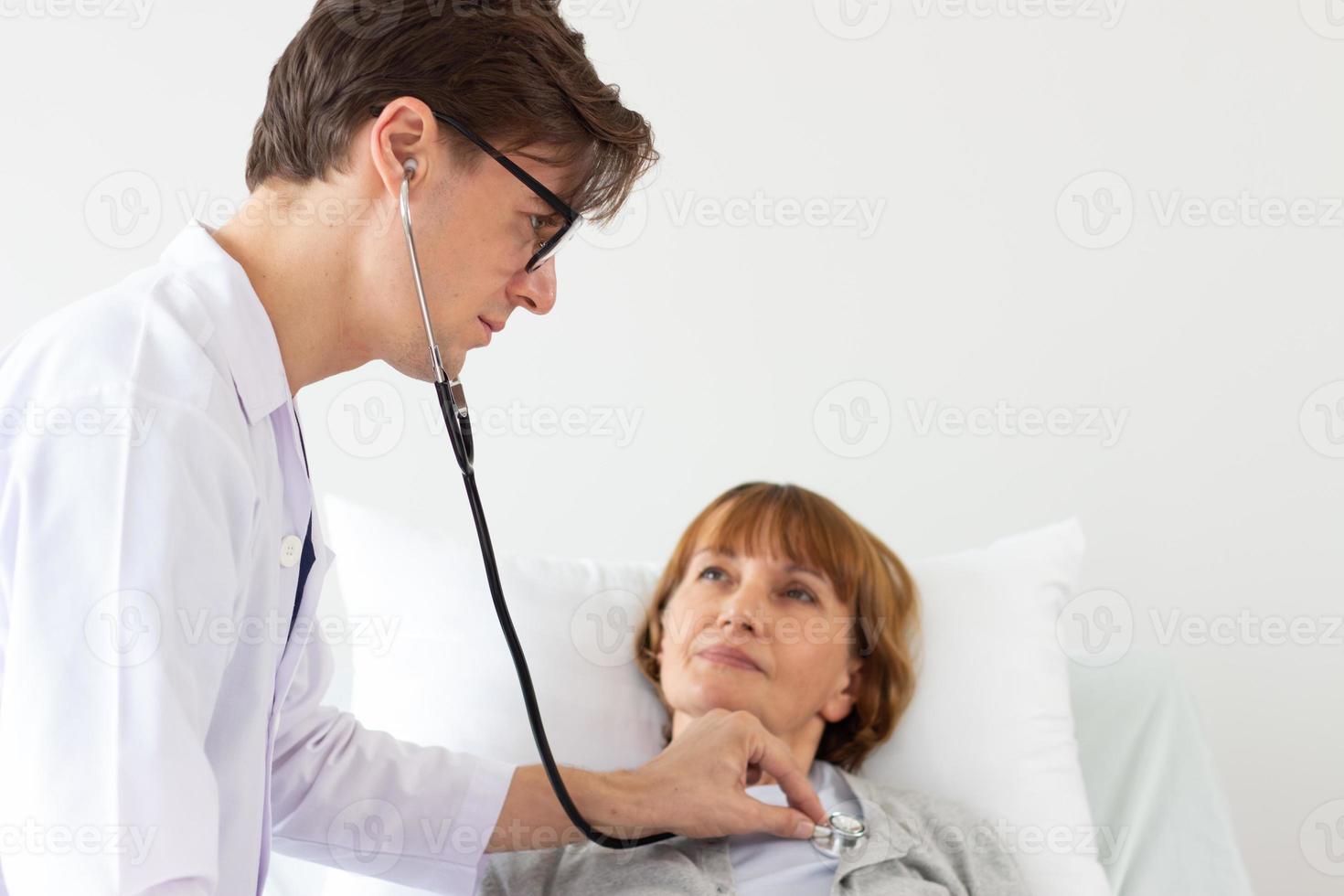 el médico está examinando al paciente en el hospital. médico varón blanco examinando a una anciana paciente blanca. foto