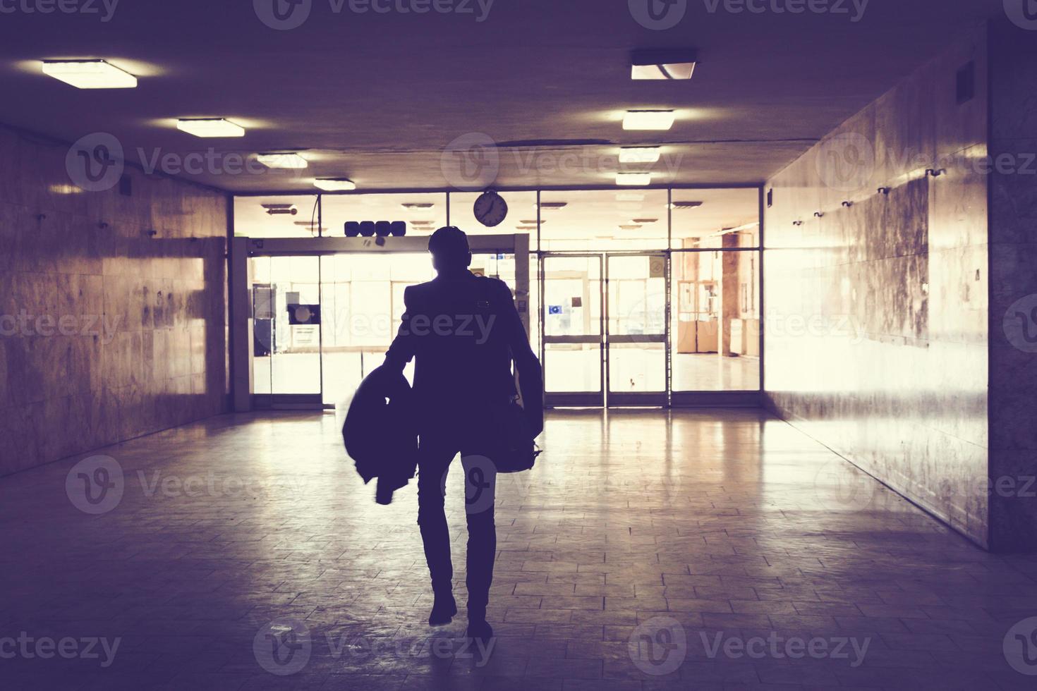 Silhouette of man walking through an empty hallway. photo