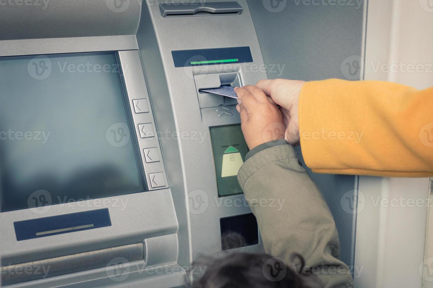 primer plano de madre e hija retirando dinero del cajero automático. foto