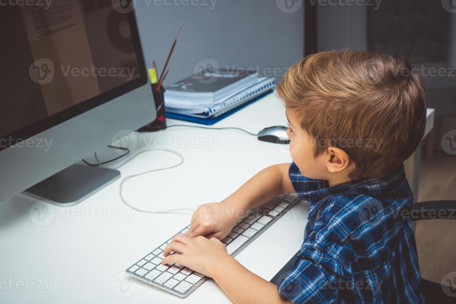 Small kid working on desktop computer. photo