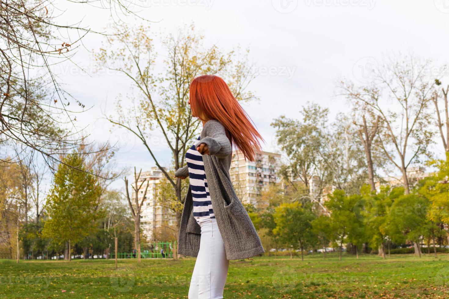 Playful woman spinning with arms outstretched during fall season