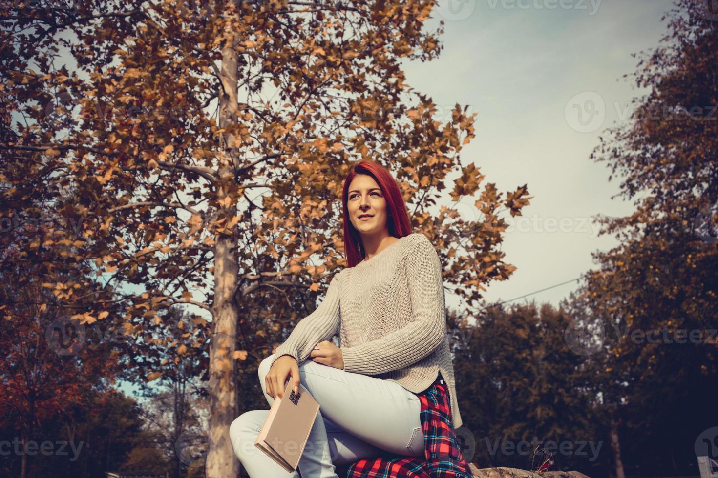 hermosa mujer pelirroja soñando despierta en el parque. foto