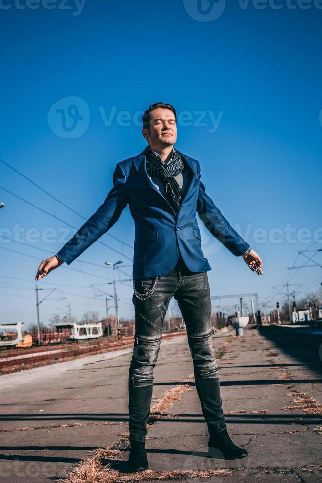 Carefree businessman standing on railway station with arms outstretched. photo