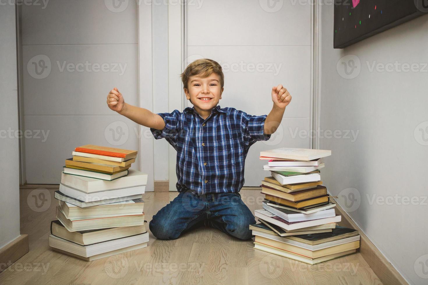 Excited kid with hands raised with books around him. photo