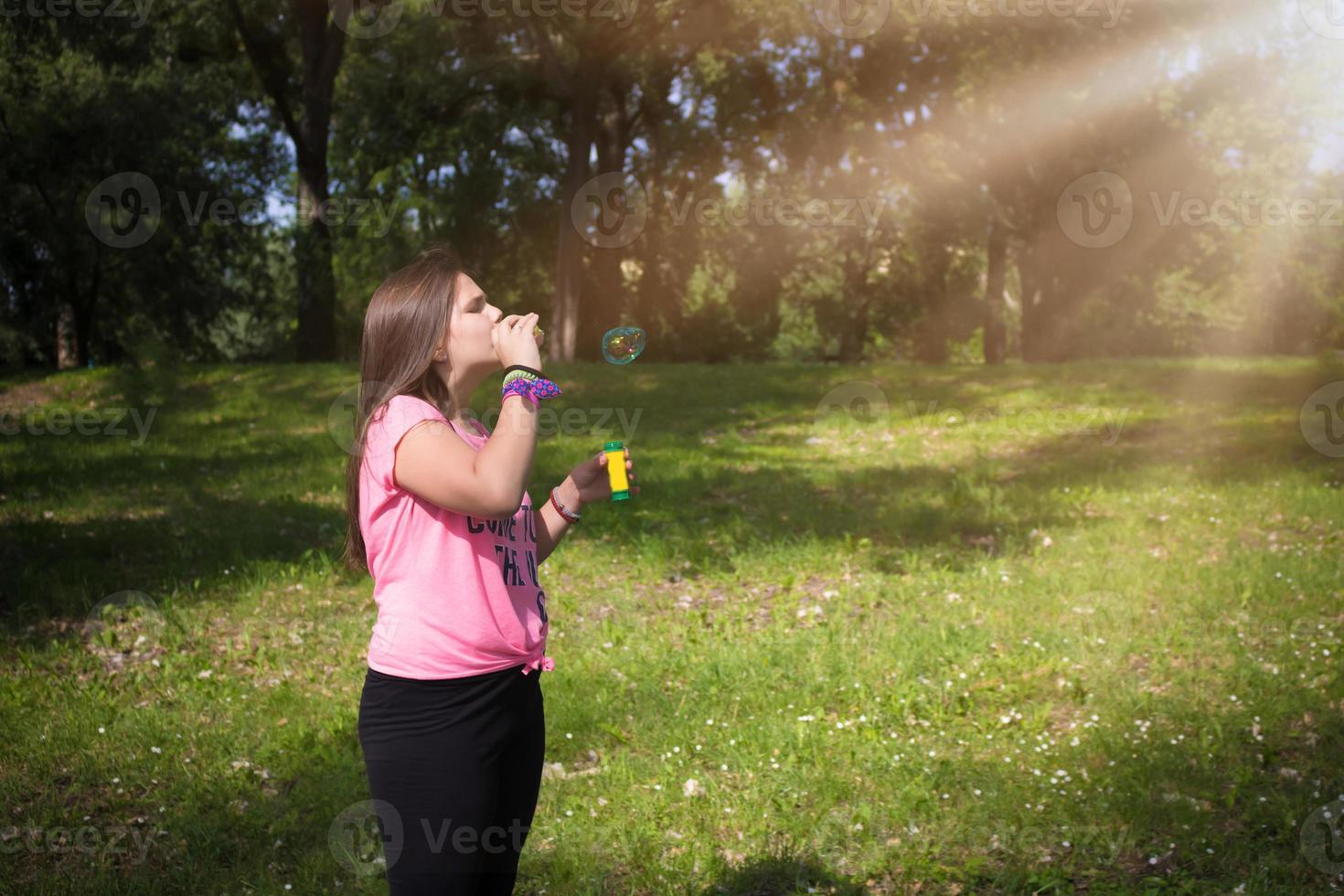 Teenage girl blowing bubbles in the park. photo