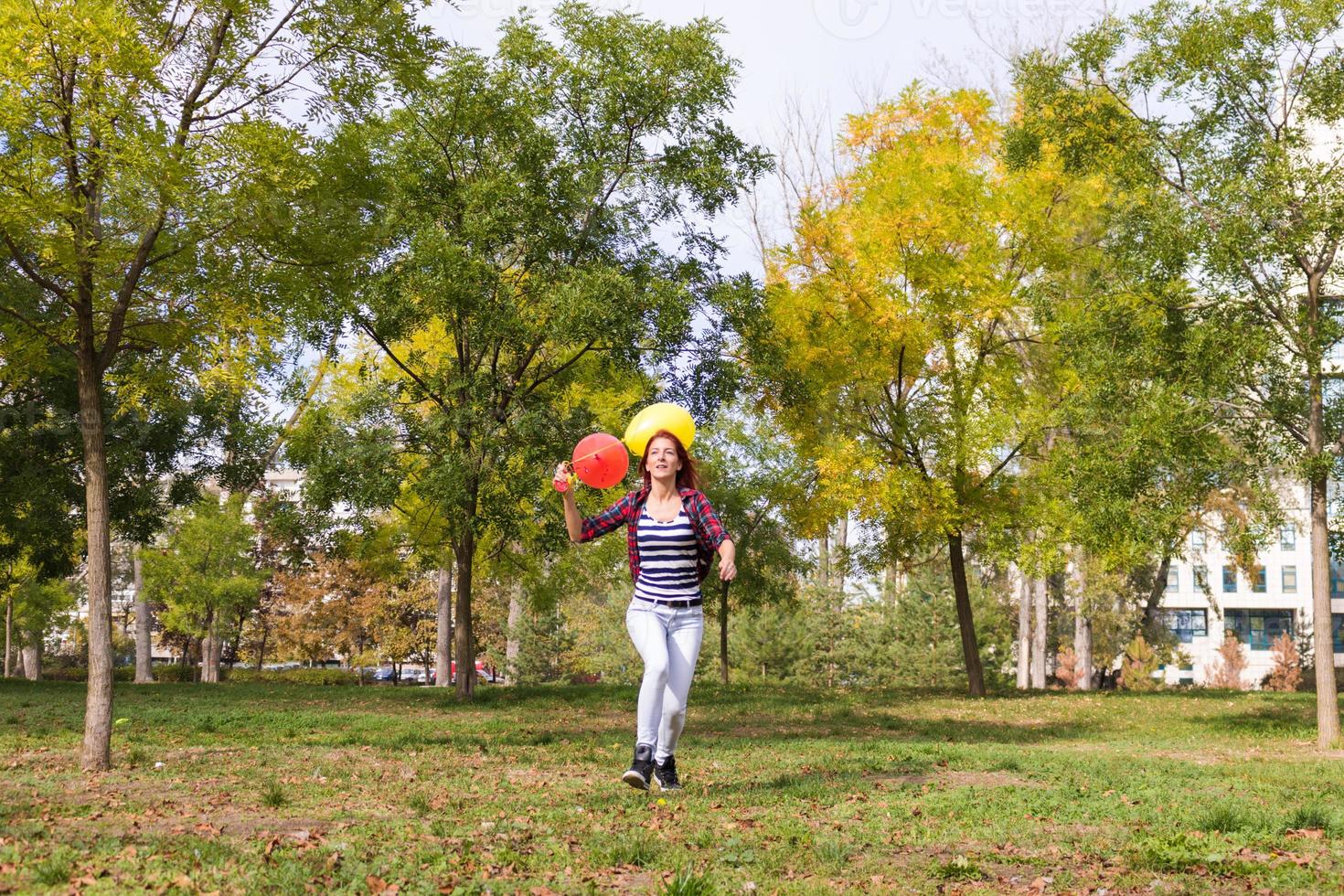 Playful woman running with balloons in the park. photo