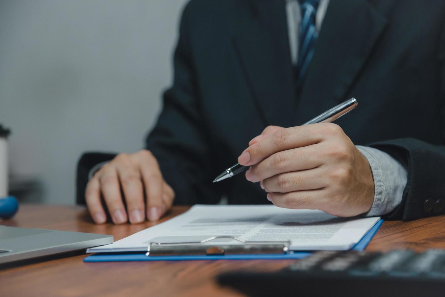 mano de hombre de negocios con pluma papeleo gráfico informe y documento gráfico financiero inversión marketing o seguro fiscal en el escritorio. foto