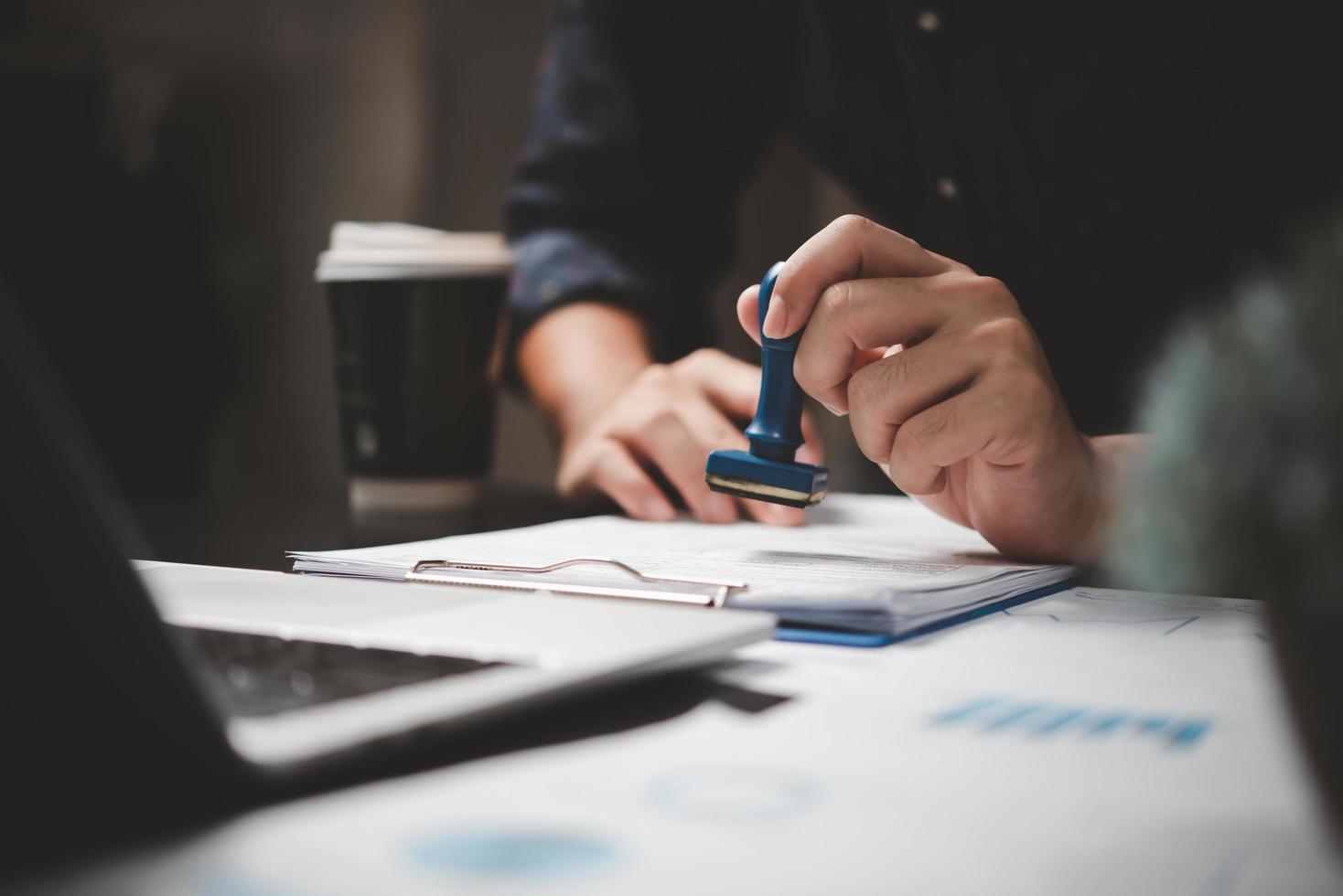 Man stamping approval of work finance banking or investment marketing documents on desk. photo
