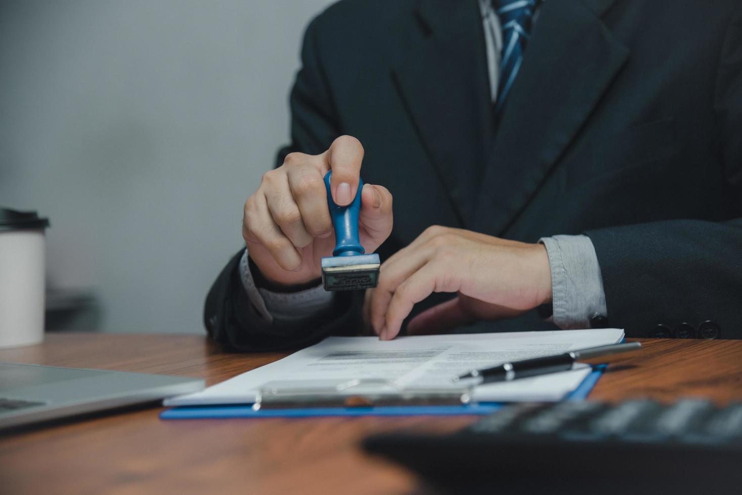 hombre que sella la aprobación de la banca de financiación del trabajo o los documentos de marketing de inversión en el escritorio. foto