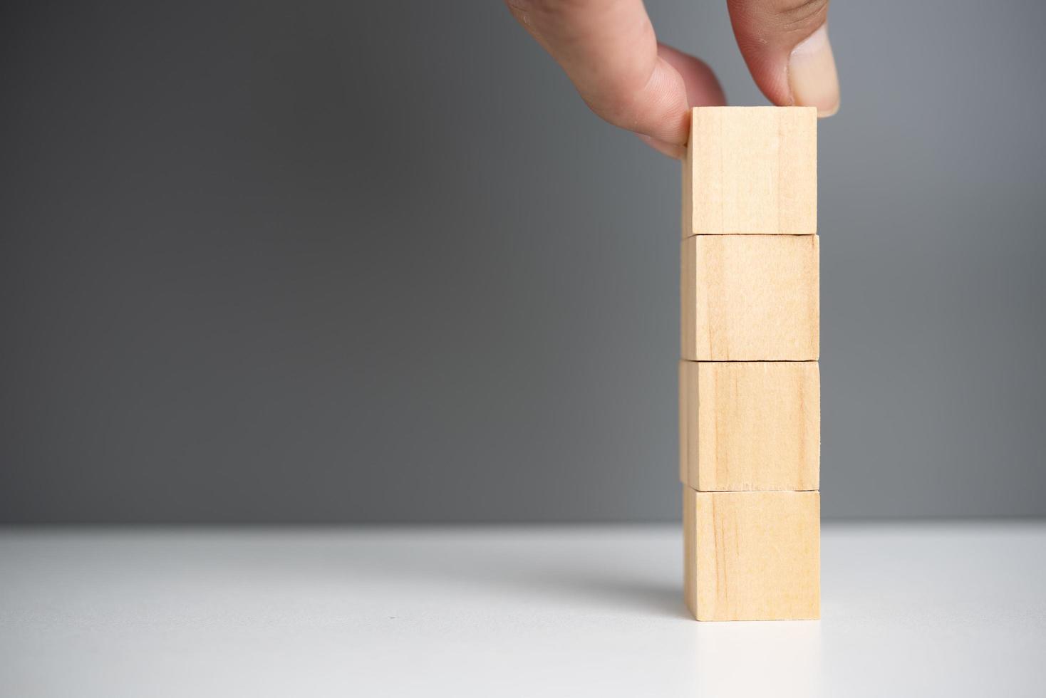 mano que sostiene el bloque de madera del cubo en blanco en el fondo. copie el espacio foto