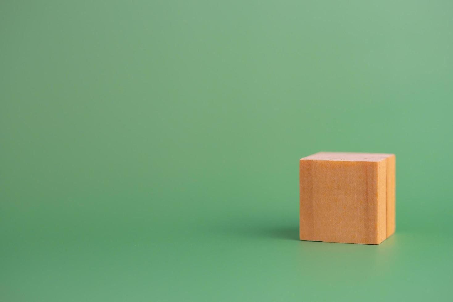 bloque de madera de cubo en blanco sobre fondo verde. copie el espacio foto