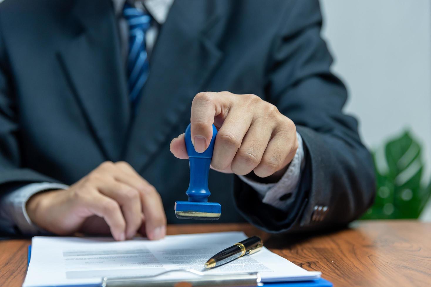 Man stamping approval of work finance banking or investment marketing documents on desk. photo