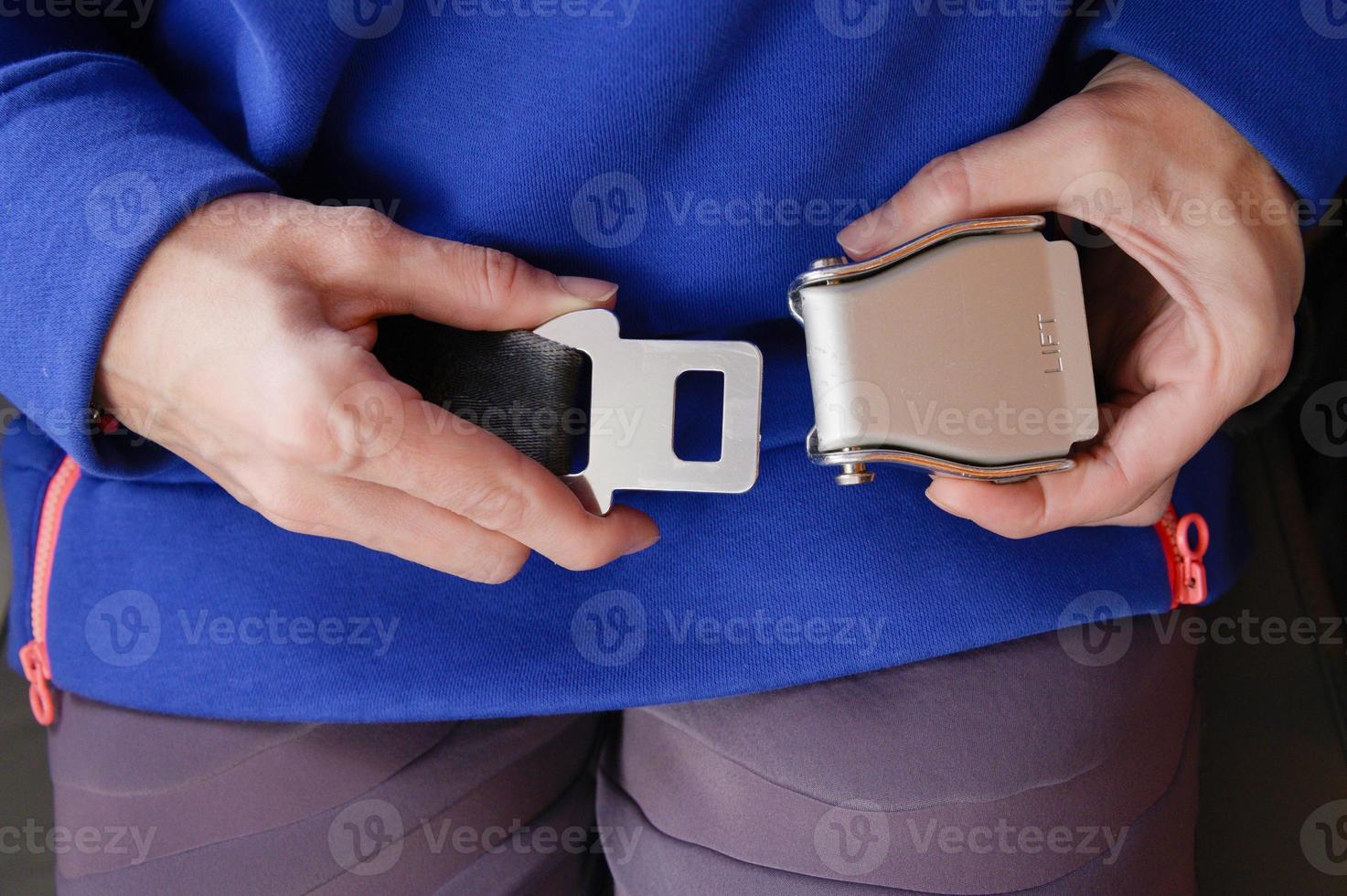 Close-up of a young woman fastens a seat belt while sitting in a passenger airplane chair by the window. The concept of safety measures for passenger flights in aircraft photo