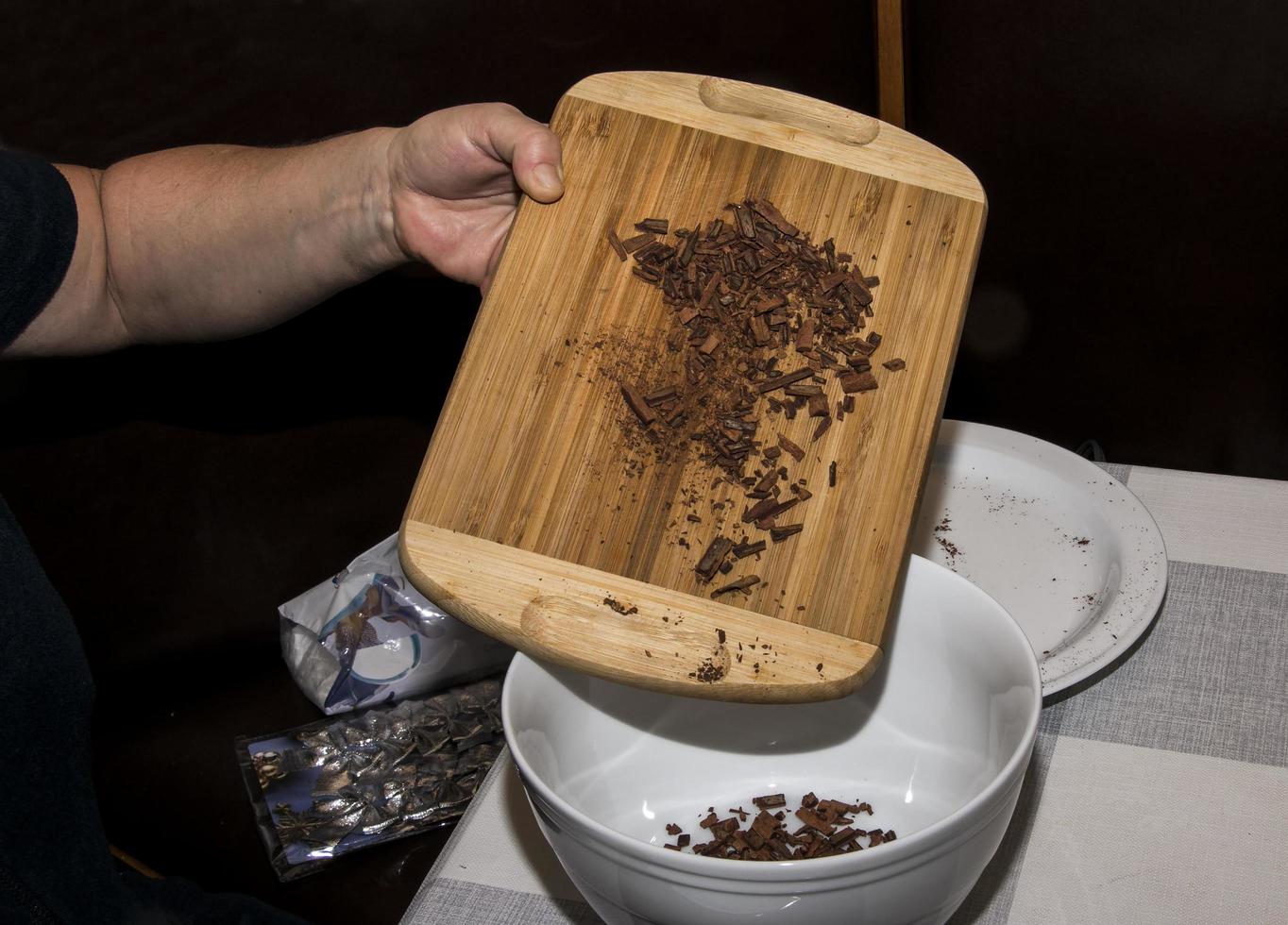 A woman's hand pours pieces of cinnamon sticks into a container for making a tea mixture. Pieces of cinnamon sticks on a wooden board. photo