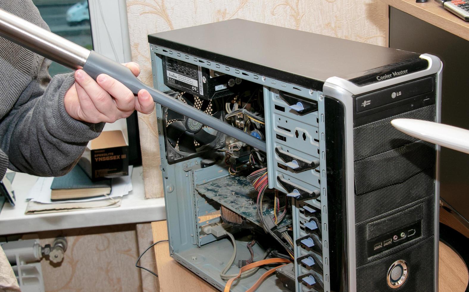 Cleaning the system unit of a desktop computer from dust using a vacuum cleaner. photo