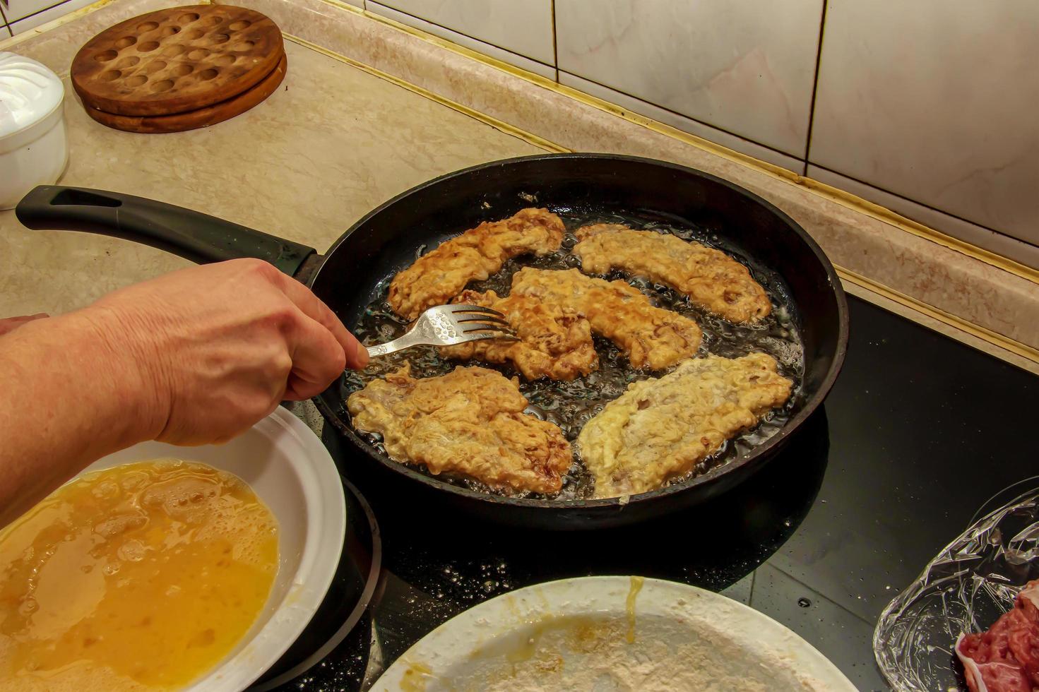 Beef chops in a pan on the stove. The process of preparing beef chops in batter photo