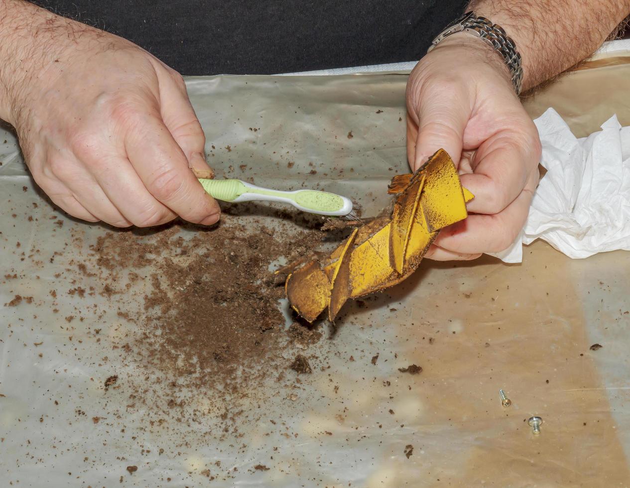 limpiando un extractor de cocina muy sucio de la suciedad con un cepillo. un hombre limpia las partes de un ventilador con un cepillo foto