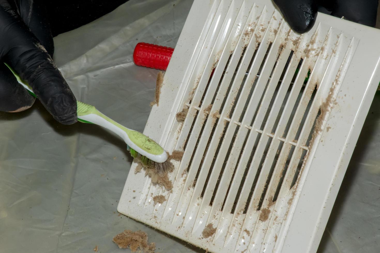 Cleaning a very dirty kitchen exhaust fan from dirt with a brush. A man cleans the parts of a fan with a brush photo