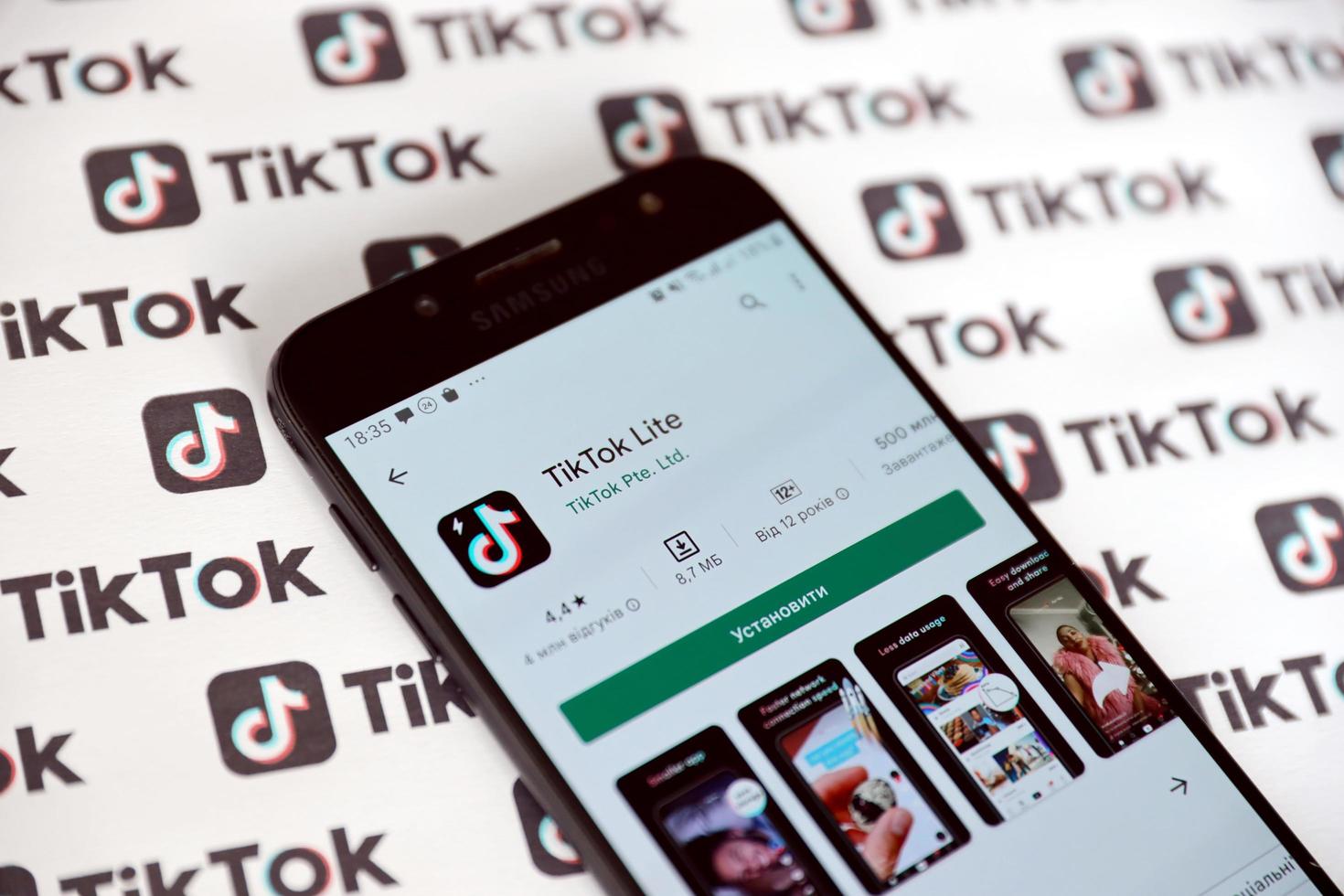 ternopil, ucrania - 2 de mayo de 2022 aplicación de teléfono inteligente tik tok en pantalla y muchos logotipos de tiktok impresos en papel. tiktok o douyin es un famoso servicio chino de alojamiento de videos de formato corto propiedad de bytedance foto