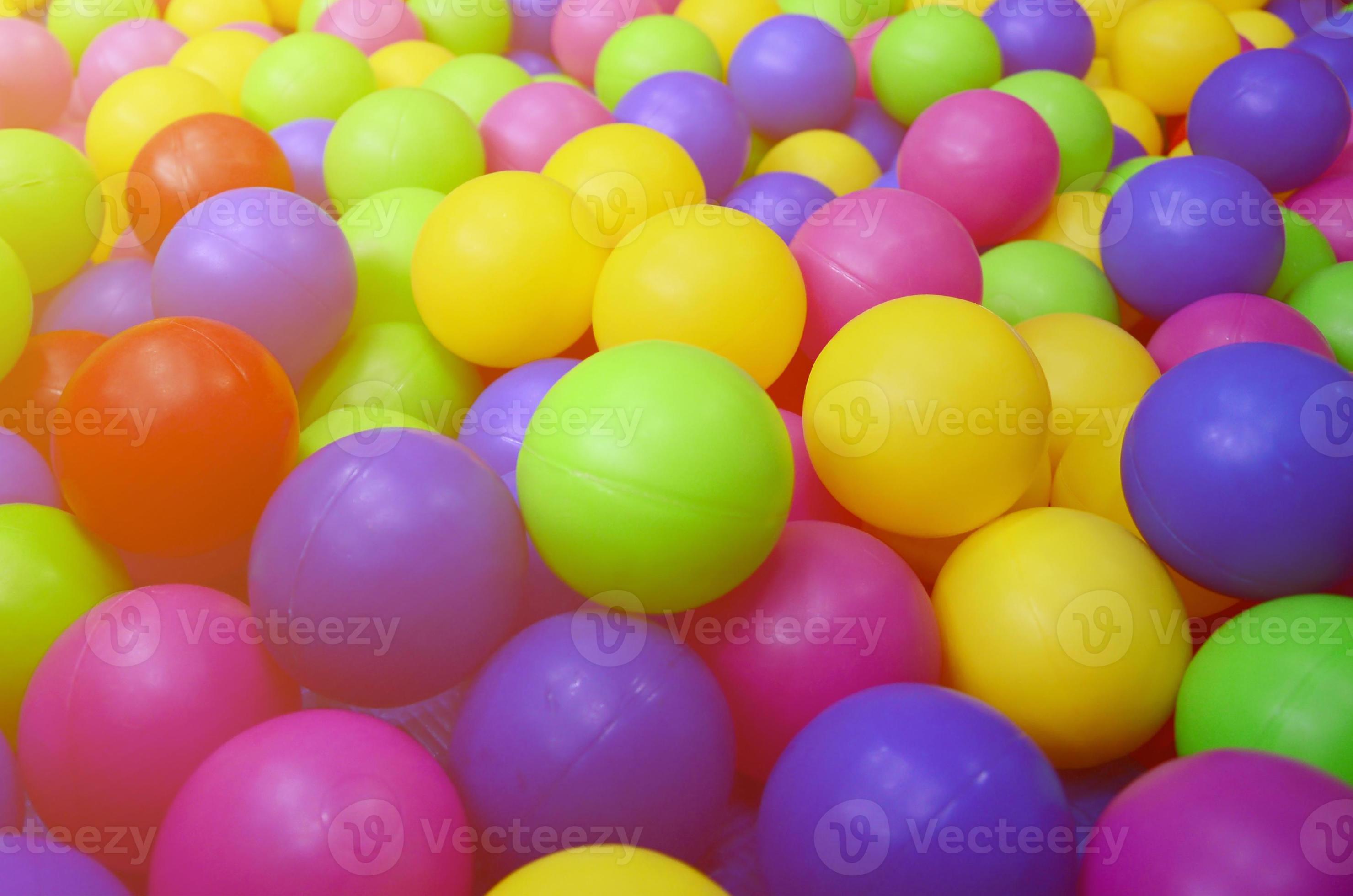 Many colorful plastic balls in a kids' ballpit at a playground. Close