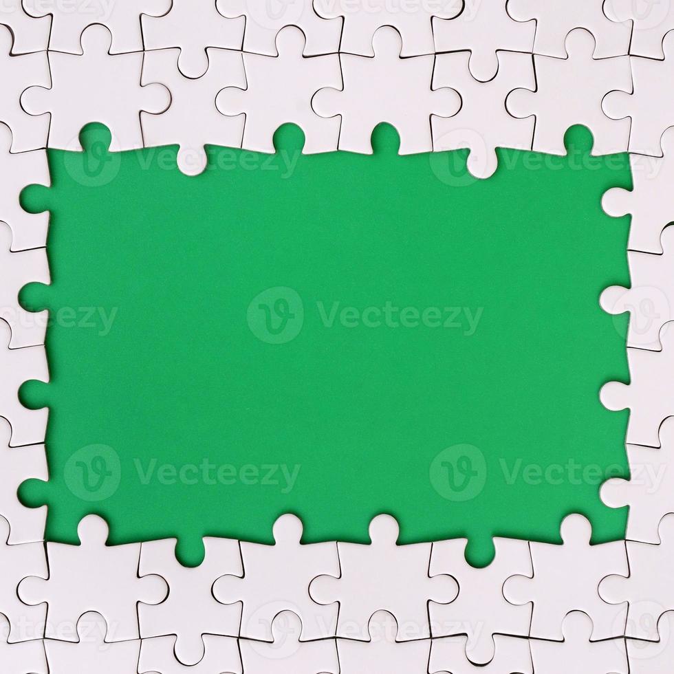 Framing in the form of a rectangle, made of a white jigsaw puzzle around the green space photo