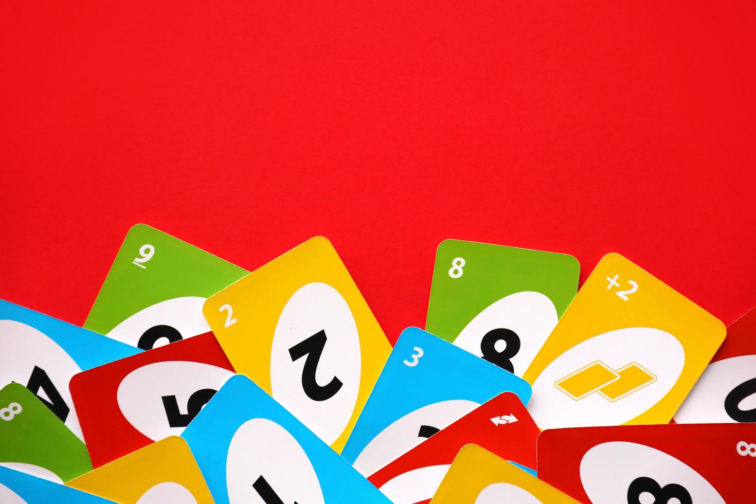 TERNOPIL, UKRAINE - MAY 15, 2022 Many colorful UNO game cards on red background. UNO is an American shedding-type card game that is played with a specially printed deck photo