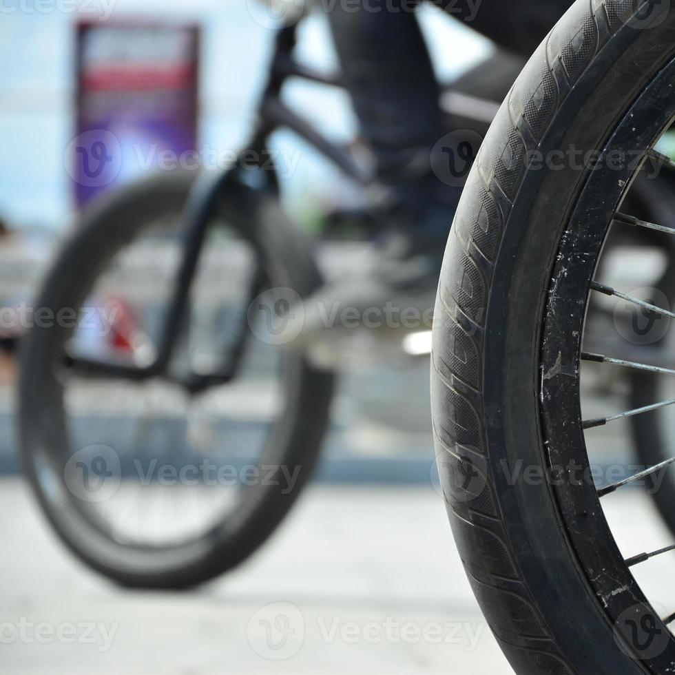 A BMX bike wheel against the backdrop of a blurred street with cycling riders. Extreme Sports Concept photo