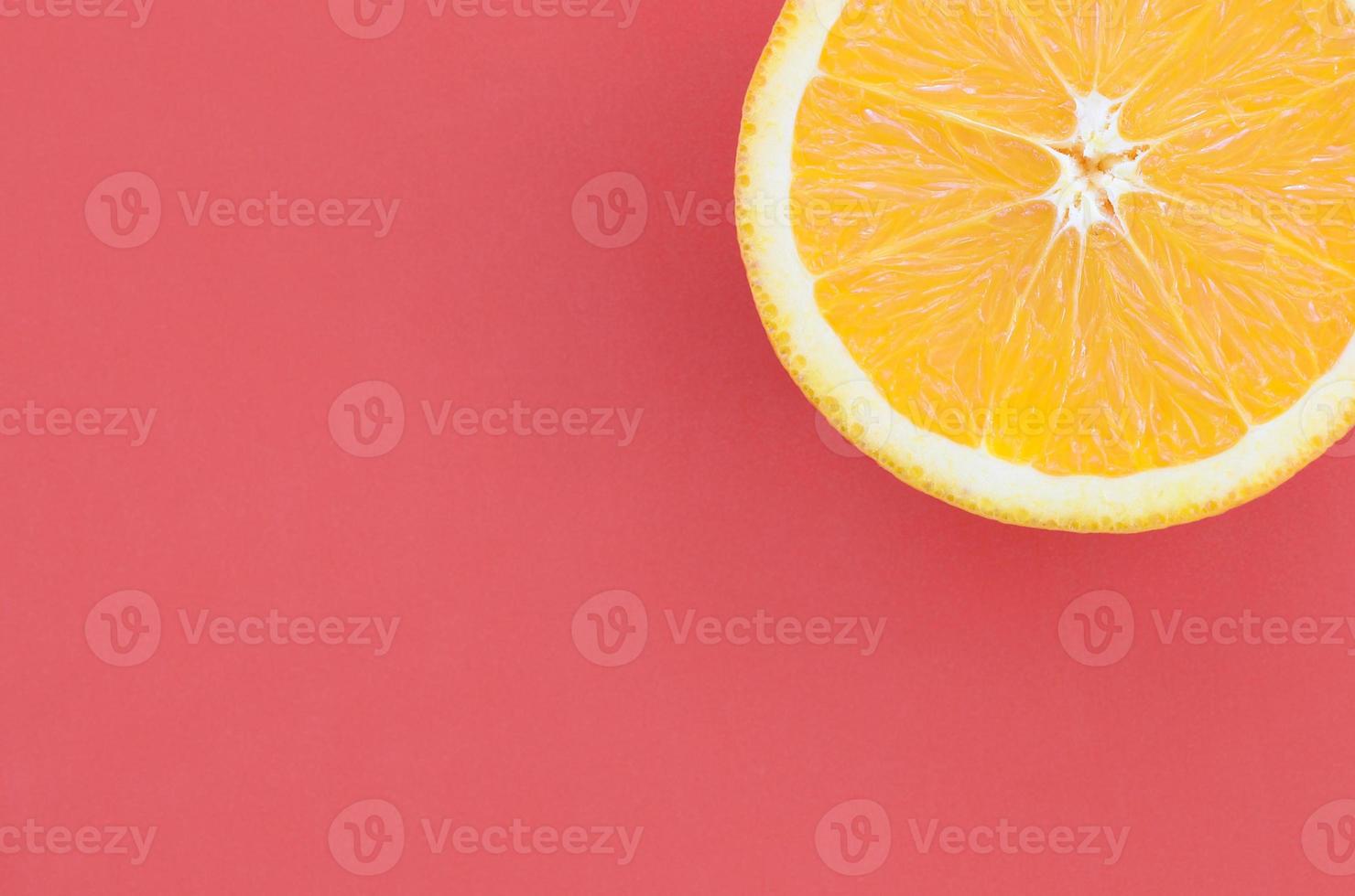 Top view of a one orange fruit slice on bright background in red color. A saturated citrus texture image photo