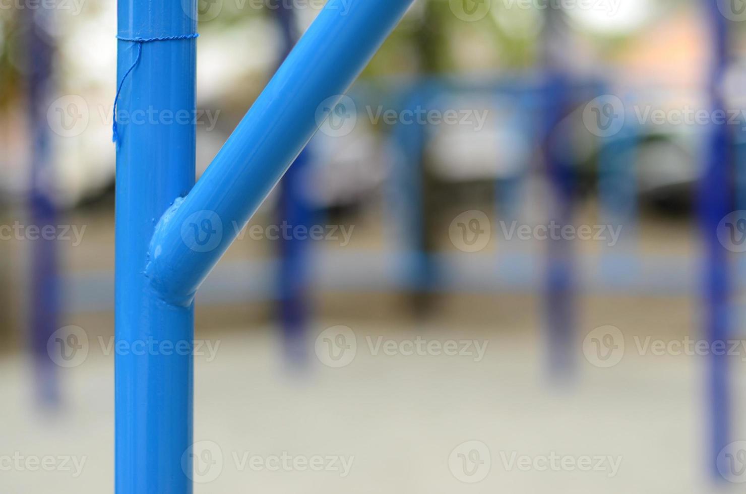 tubos de metal azul y barras transversales contra un campo de deportes callejeros para entrenar en atletismo. equipo de gimnasia atlética al aire libre. foto macro con enfoque selectivo y fondo extremadamente borroso