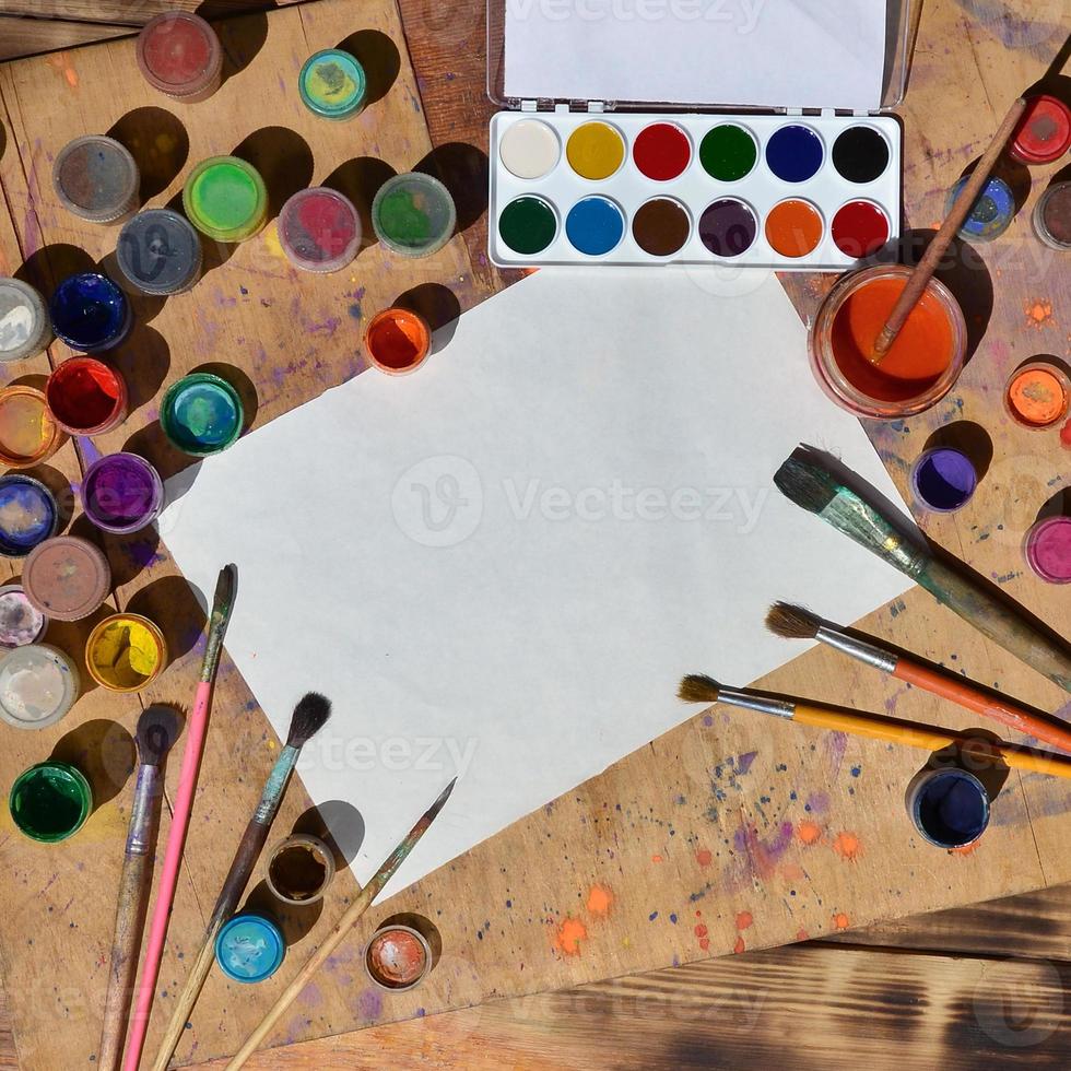 Still life with blank paper, brushes and jars of watercolor and gouache paint photo