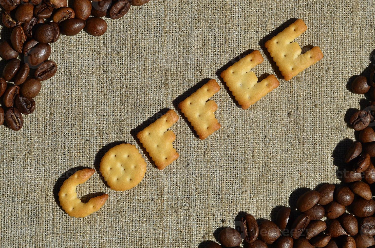 Coffee. The word from the edible letters lies on the gray canvas with coffee beans photo