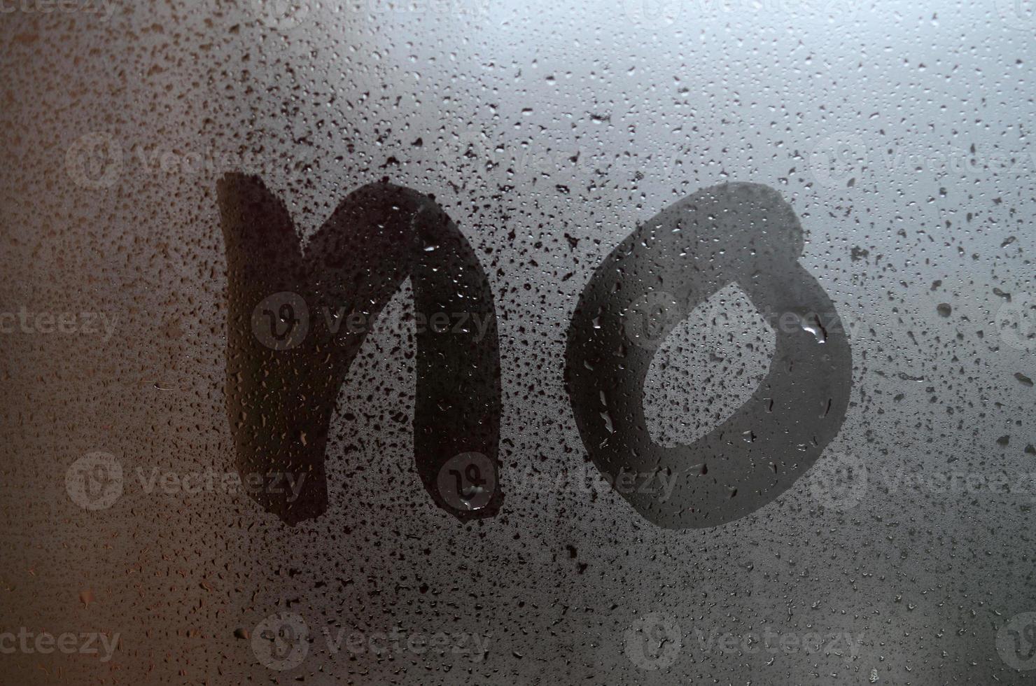 The English word No is written with a finger on the surface of the misted glass photo