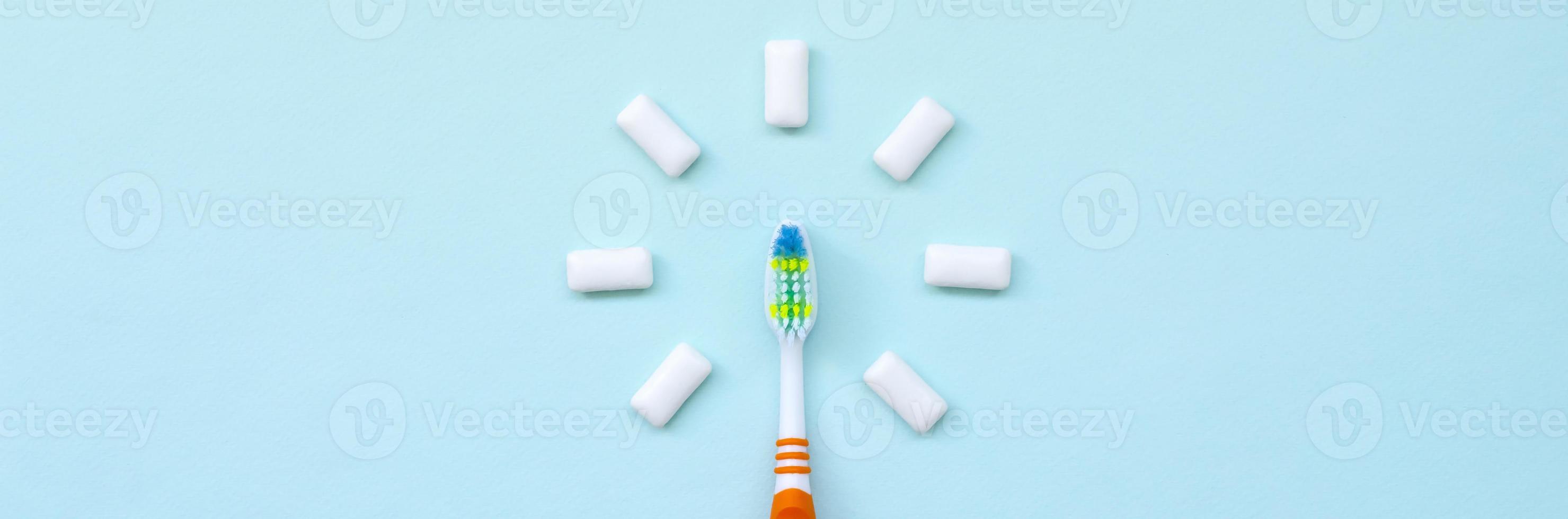 Toothbrush and chewing gums lie on a pastel blue background. Top view, flat lay. Minimal concept photo
