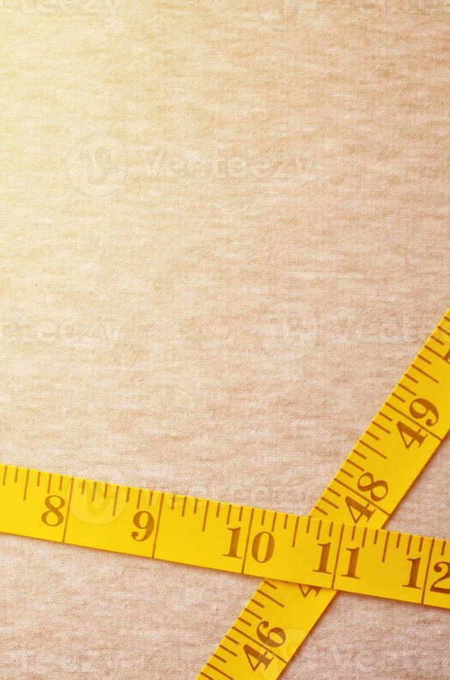 Yellow measuring tape lies on a gray knitted fabric photo