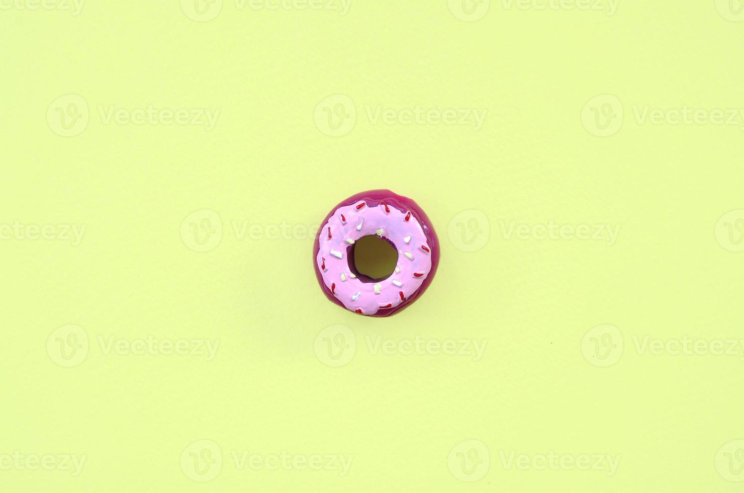 Single small plastic donut lies on a pastel colorful background. Flat lay minimal composition. Top view. photo