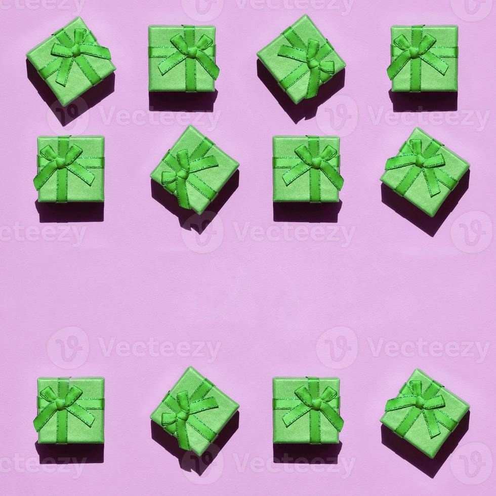 Many small green gift boxes on texture background of fashion trendy pastel pink color paper photo