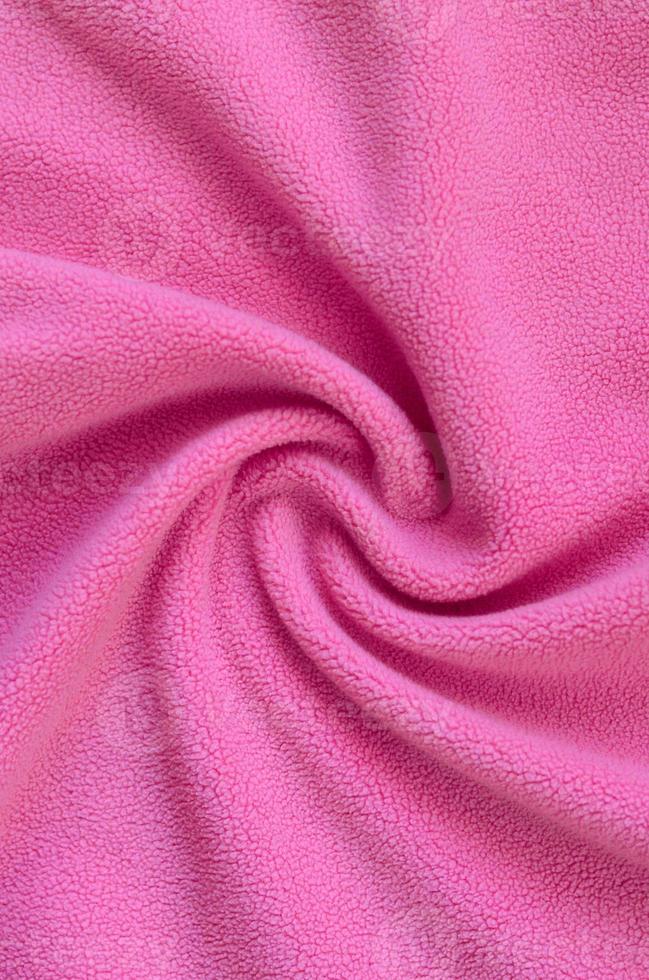 The blanket of furry pink fleece fabric. A background of light pink soft plush fleece material with a lot of relief folds photo