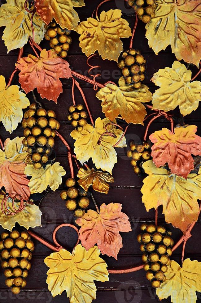 A photograph of forged grapes, painted in warm orange tones on a wooden background. Background image on the topic of winemaking or viticulture photo